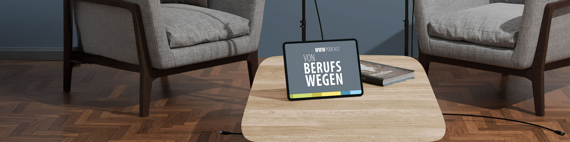 Zwei Sessel mit Mikrofonen. Davor steht ein Tisch mit einem Tablet auf dem der Podcast angezeigt wird.
